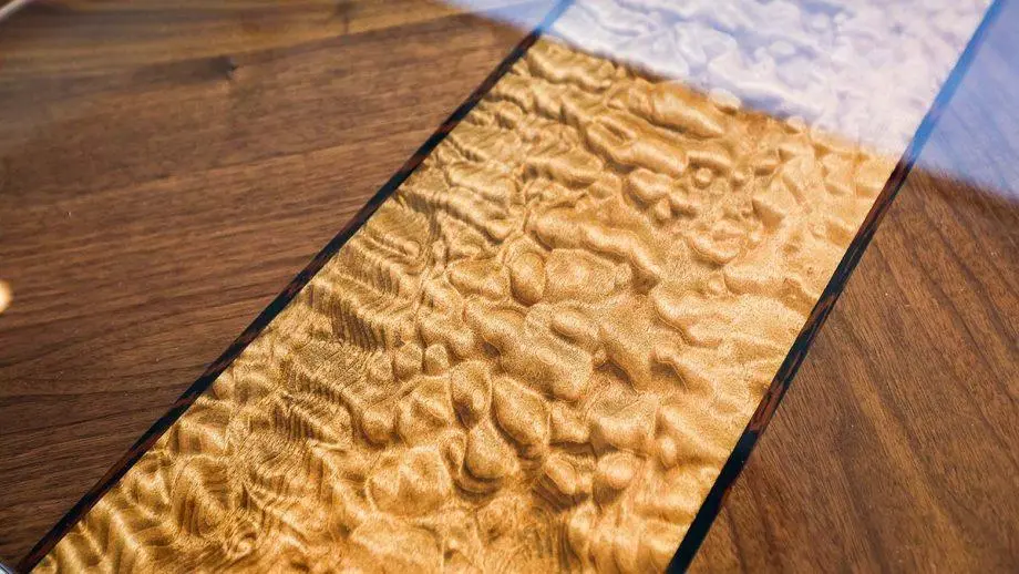 Wooden tabletop featuring a textured resin inlay with a wavy pattern, reflecting light and enhancing the natural wood grains.
